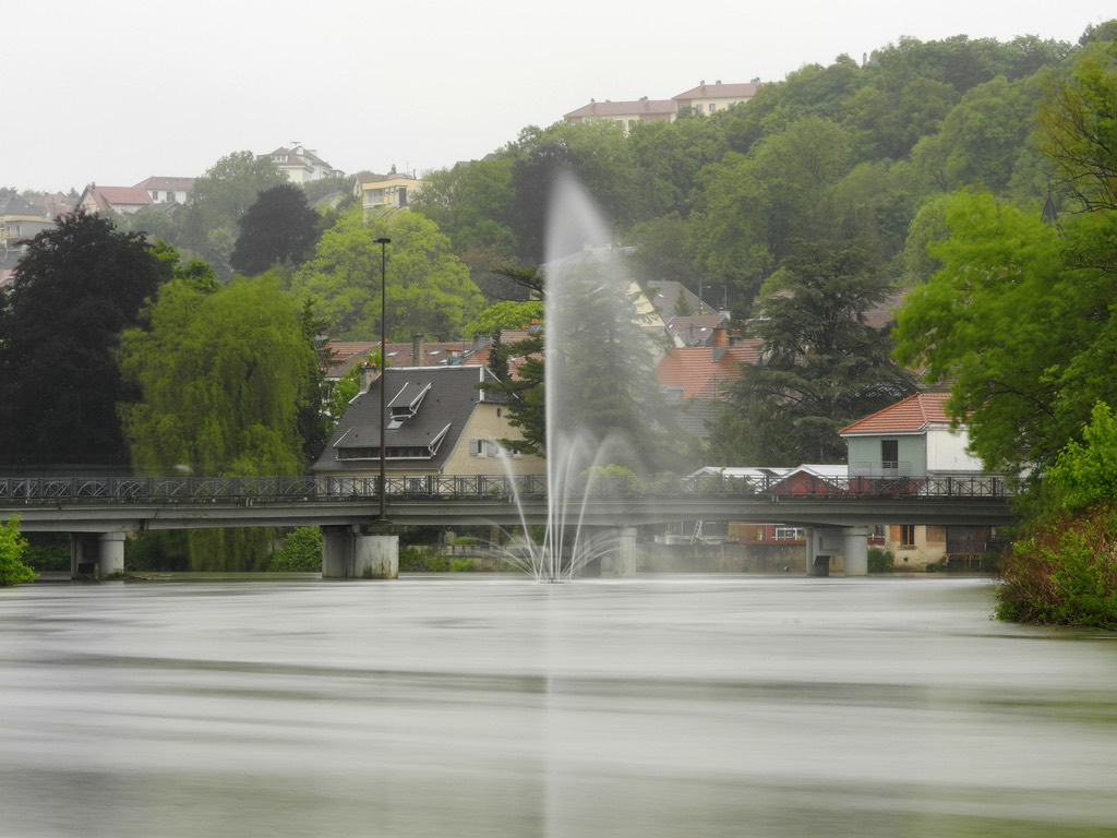 Rivière Allan à Montbéliard, avec une passerelle et une fontaine au premier plan.
