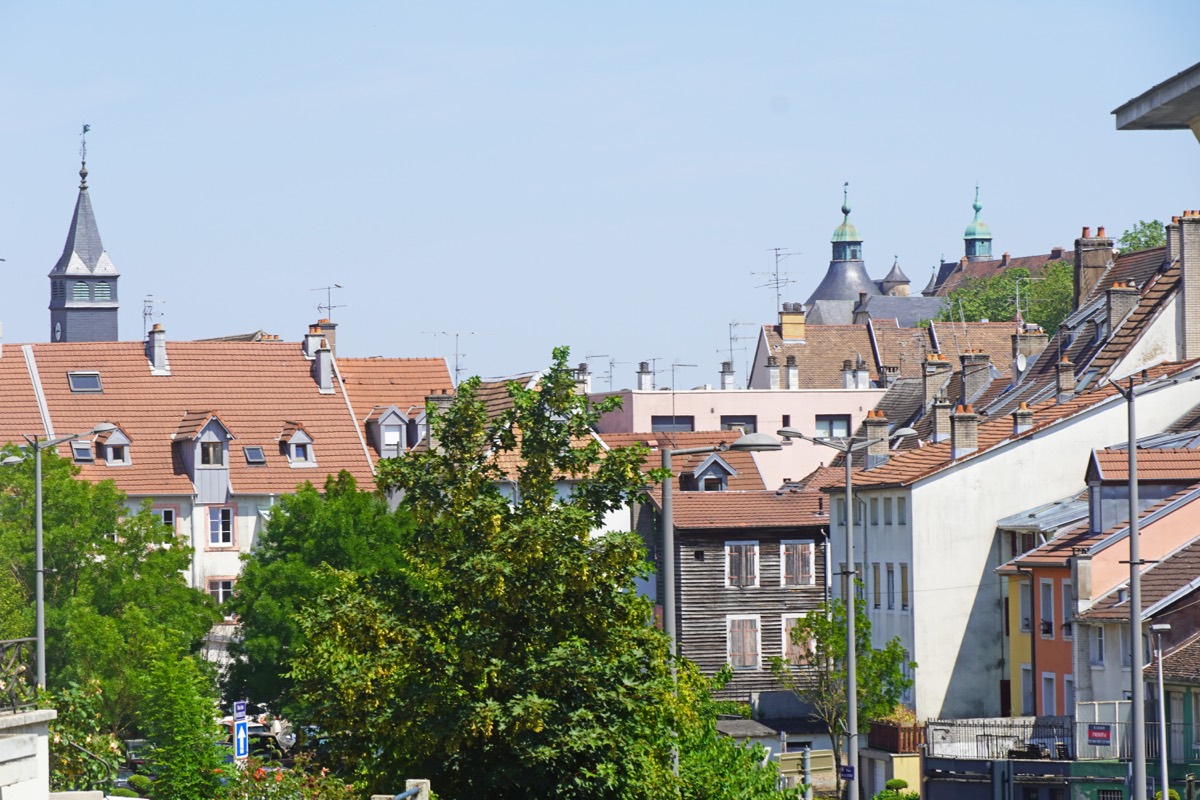Toits et immeubles du centre de Montbéliard, avec les tours du château en arrière-plan.